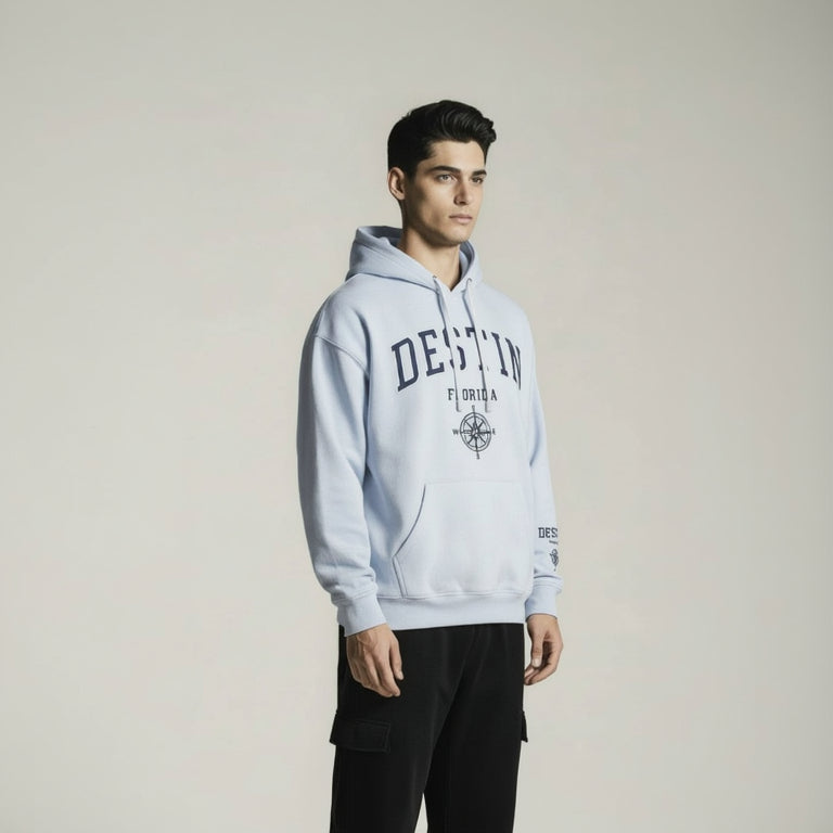 Man wearing a light gray hoodie with branding on a plain background