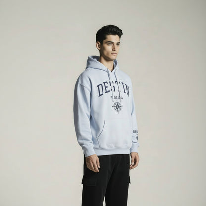 Man wearing a light gray hoodie with branding on a plain background