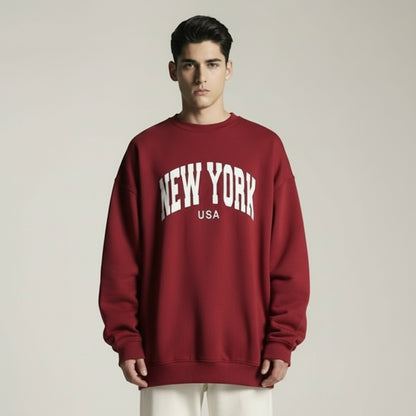 Person wearing a red sweatshirt with 'New York USA' text on a plain background